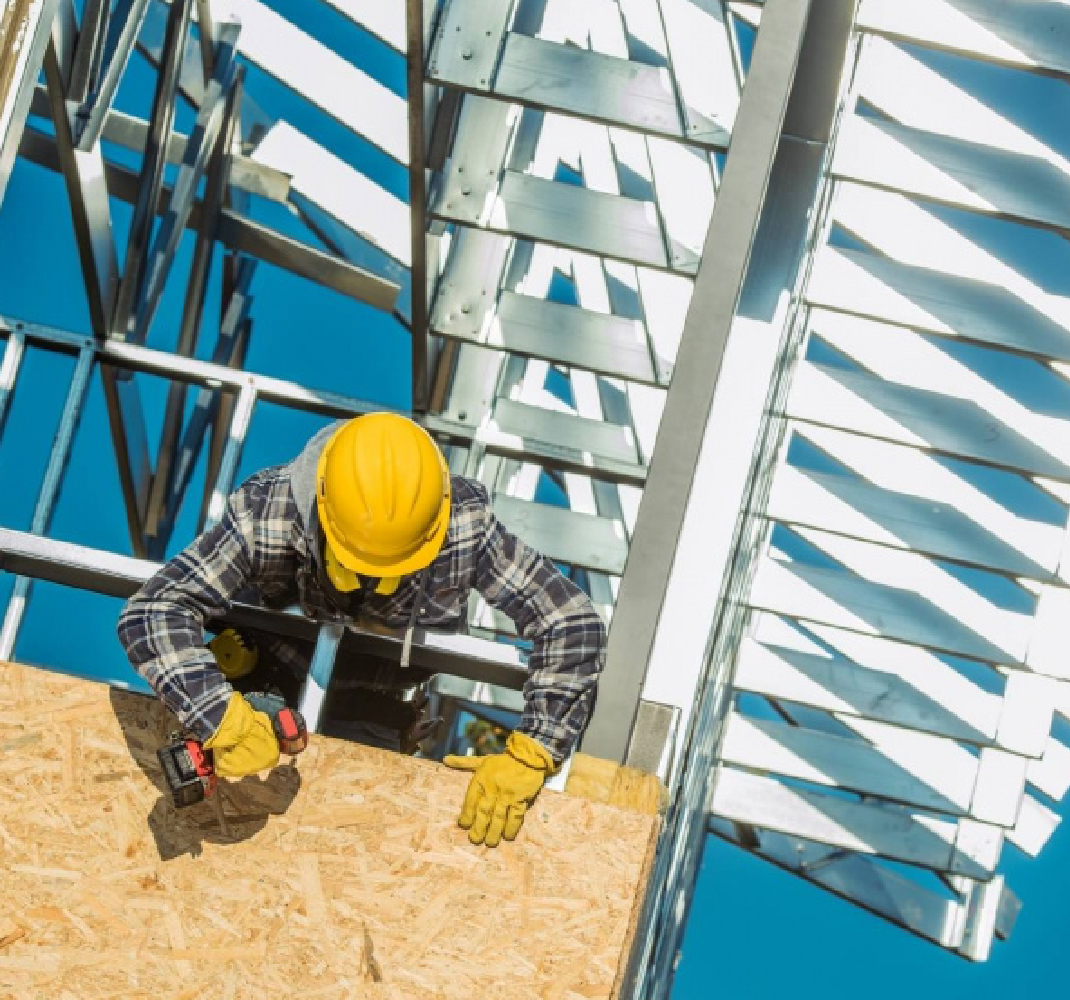 Image of a construction worker safely hanging on the side of a building fastening wood siding to metal struts